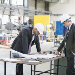 Businessmen examining blueprint at workbench in metal industry